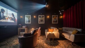 Ein gemütliches Kino mit großer Leinwand, bequemen Sitzen und gerahmten Postern an den Wänden.