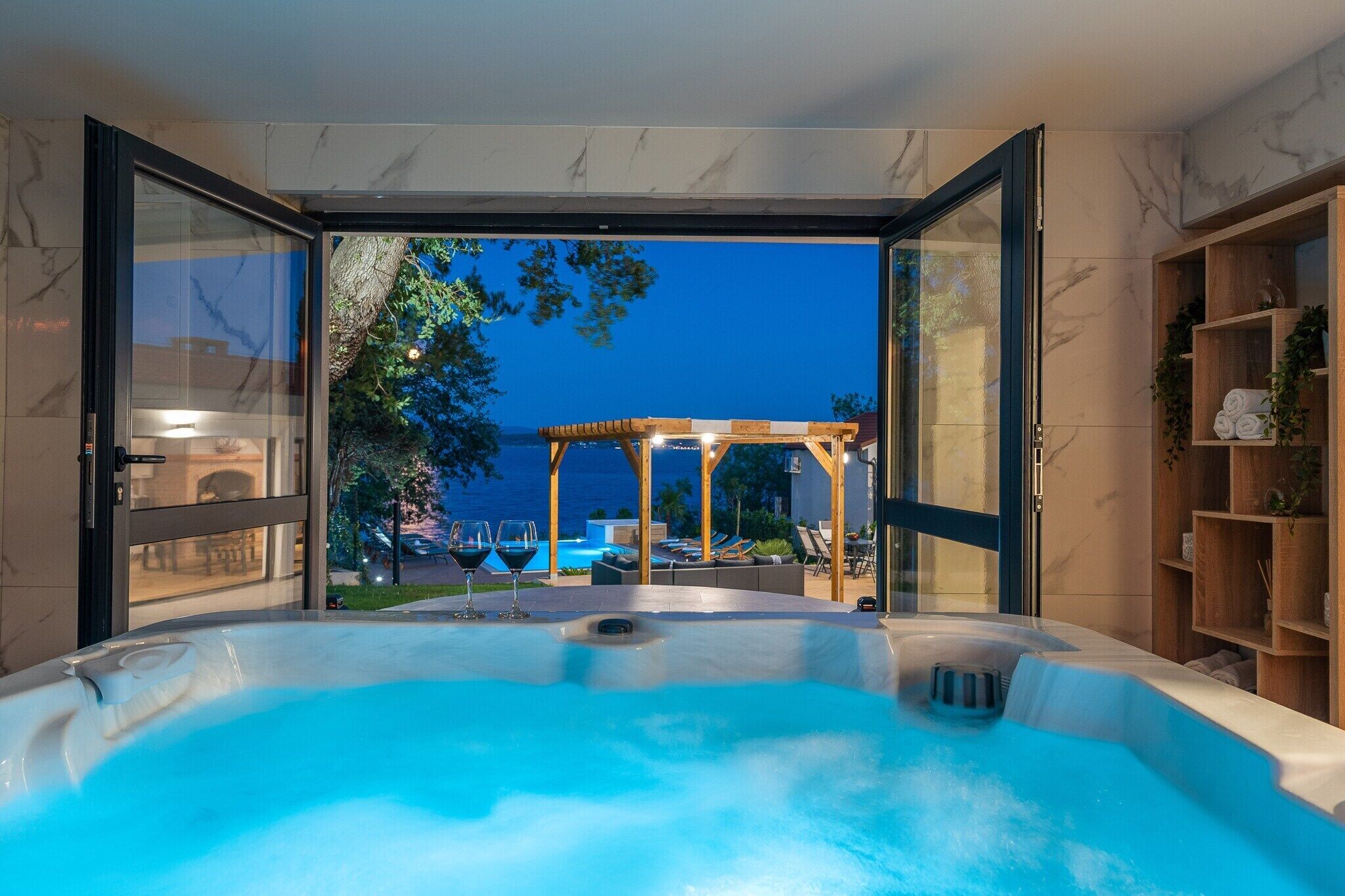 Un bain à remous avec vue sur une piscine et un espace de détente extérieur.