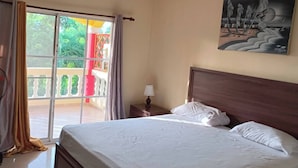 A hotel room with a bed, a nightstand, a lamp, a ceiling fan, and a painting on the wall. - Room-lady Room in Puntacana (Punta Cana)