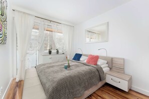 Ein modernes Schlafzimmer mit Bett, Nachttisch und einem Fenster mit Vorhängen.