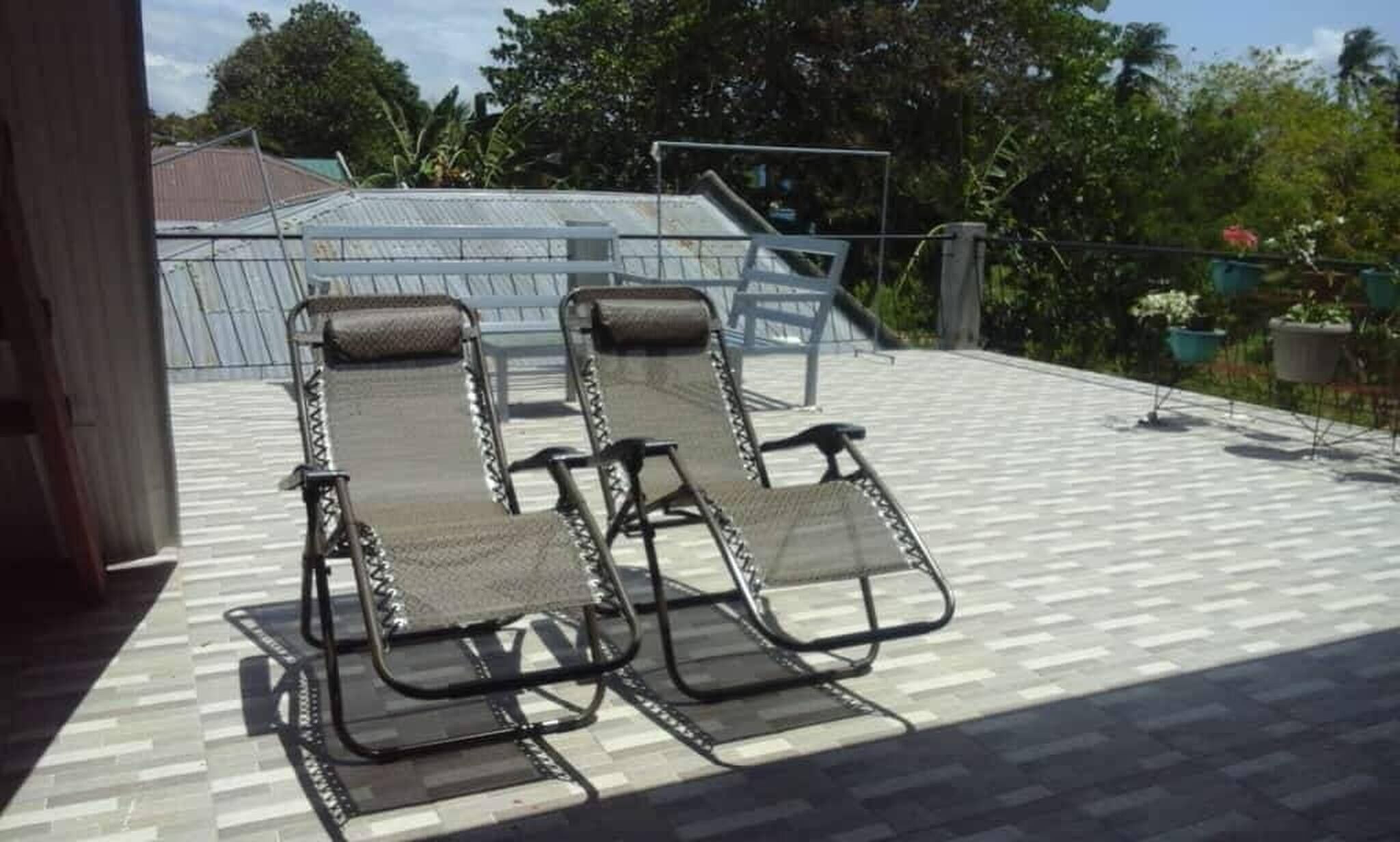Een terras op het dak met twee lounge fauteuils en een metalen hekwerk.