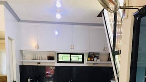 A modern kitchen with white cabinets, a black countertop, and a built-in microwave. - A Unique and Cozy Wholehouse in Babak Samal Island (Samal)