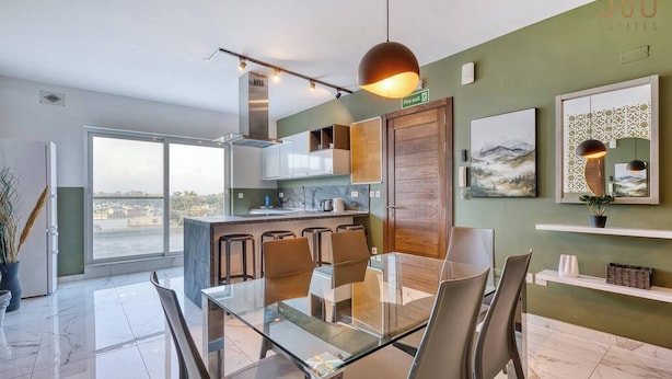 Een moderne keuken met een glazen eettafel en stoelen, uitzicht door grote ramen en een bord met daarop de tekst branddeur.