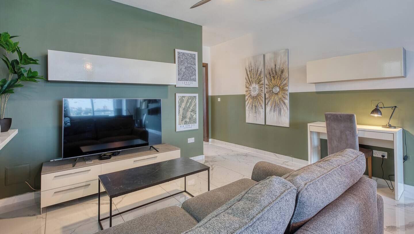 Un salon moderne avec un téléviseur à écran plat, un canapé, une table basse et des œuvres d’art accrochées aux murs.