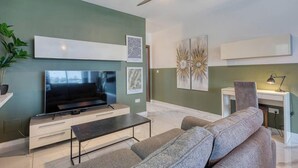 Een moderne woonkamer met een flatscreen televisie, een bank, een salontafel en kunstwerken aan de muur.