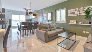 Een moderne woonkamer met een bank, salontafel en eethoek.