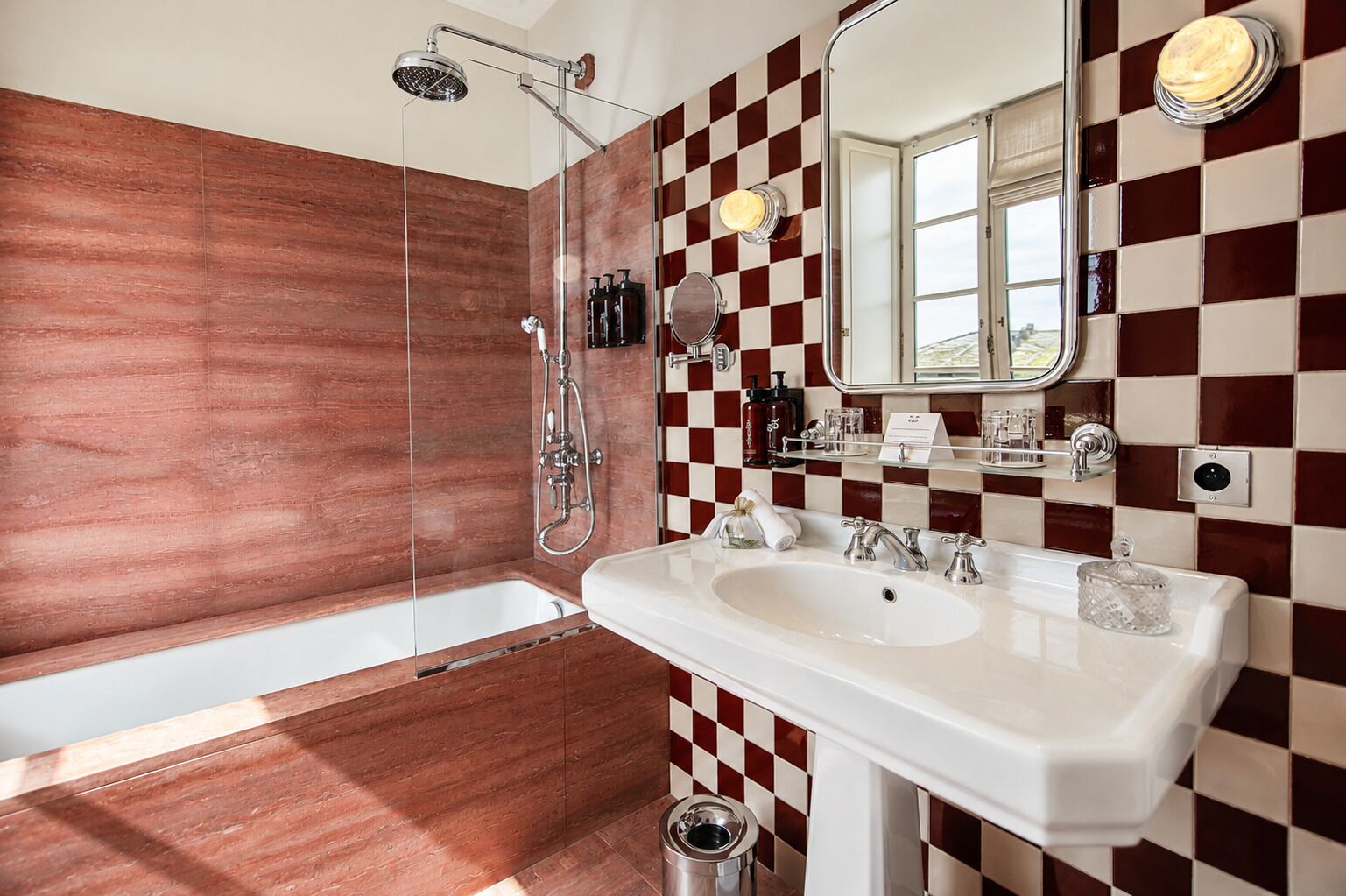 Un baño con detalles de pared a cuadros, un lavabo blanco, una ducha y un espejo.