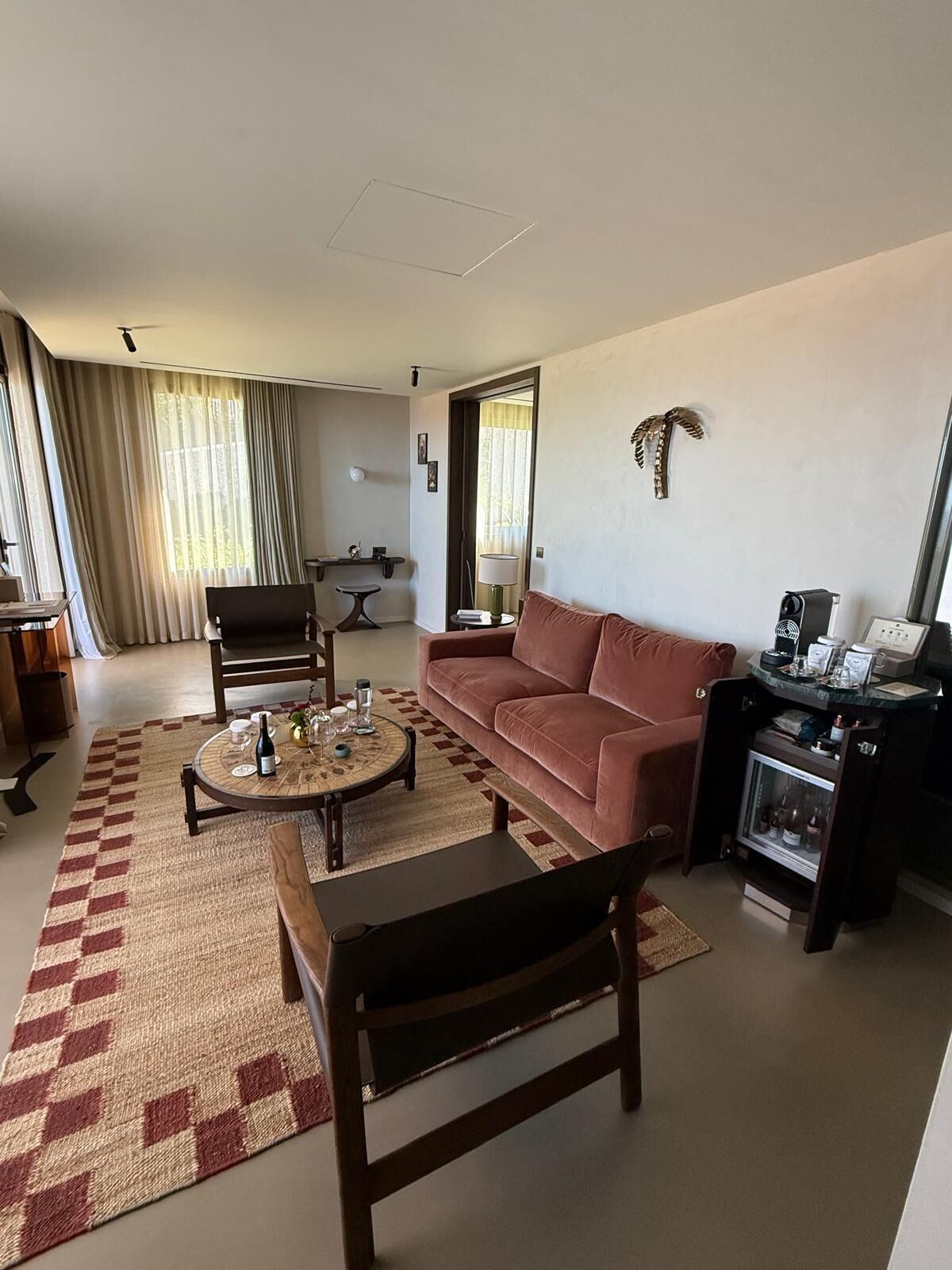 A living room with a sofa, coffee table, and chairs, a kitchen area with a refrigerator, and a dining area with a table and chairs.