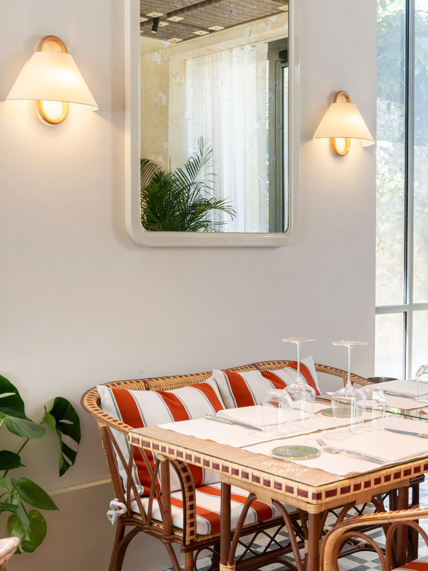 A dining area with a table set for four, surrounded by wicker chairs with striped cushions.