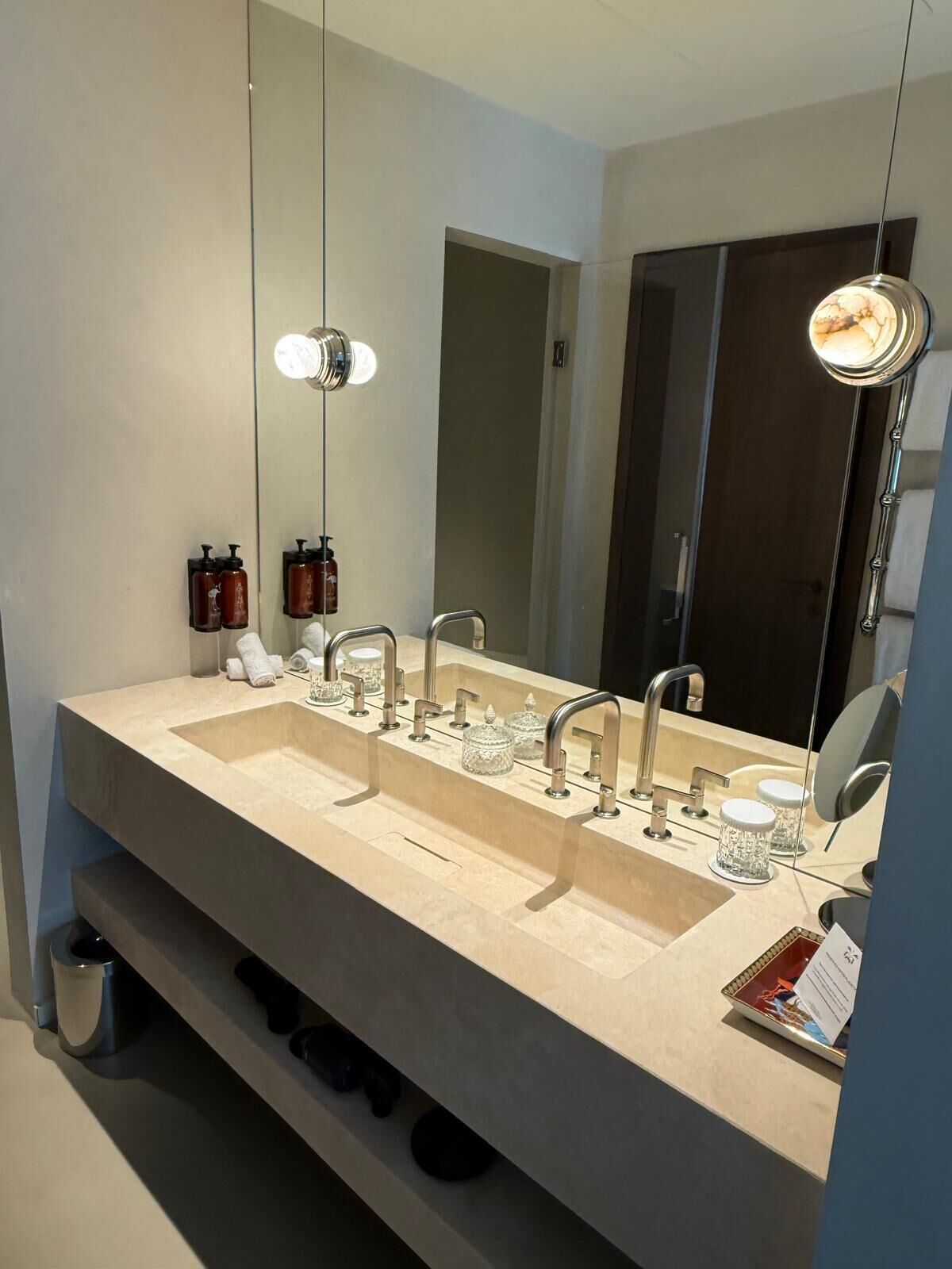 A modern bathroom with two sinks, a large mirror, and overhead lighting.