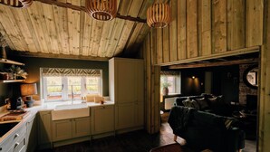 L’intérieur d’un chalet rustique comprenant une cuisine, un coin repas et un salon.