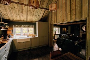 Interno di un rustico chalet con cucina, zona pranzo e soggiorno.