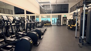 Un gimnasio con cintas de correr, máquinas de pesas y un espejo grande.