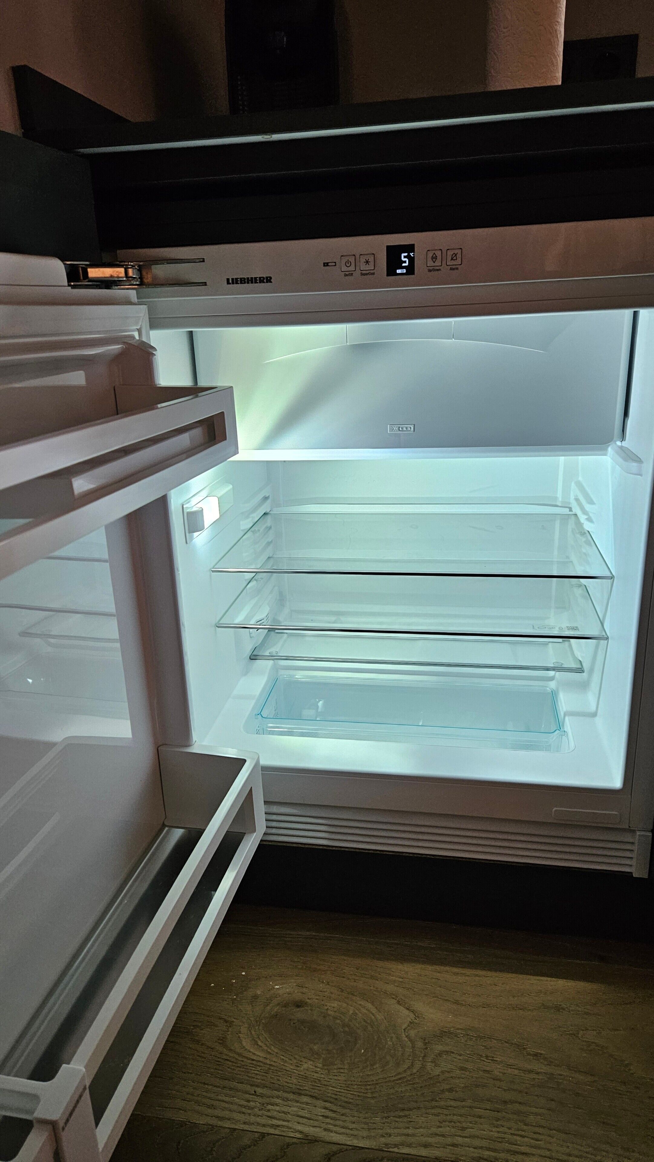 Ein offener Kühlschrank mit mehreren Ablagen und einer digitalen Anzeige.