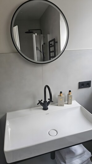 A bathroom with a white sink, black faucet, and a round mirror. - Holiday Home “Kavalierhaus – Burg Heppingen” with Wi-Fi (Bad Neuenahr-Ahrweiler)