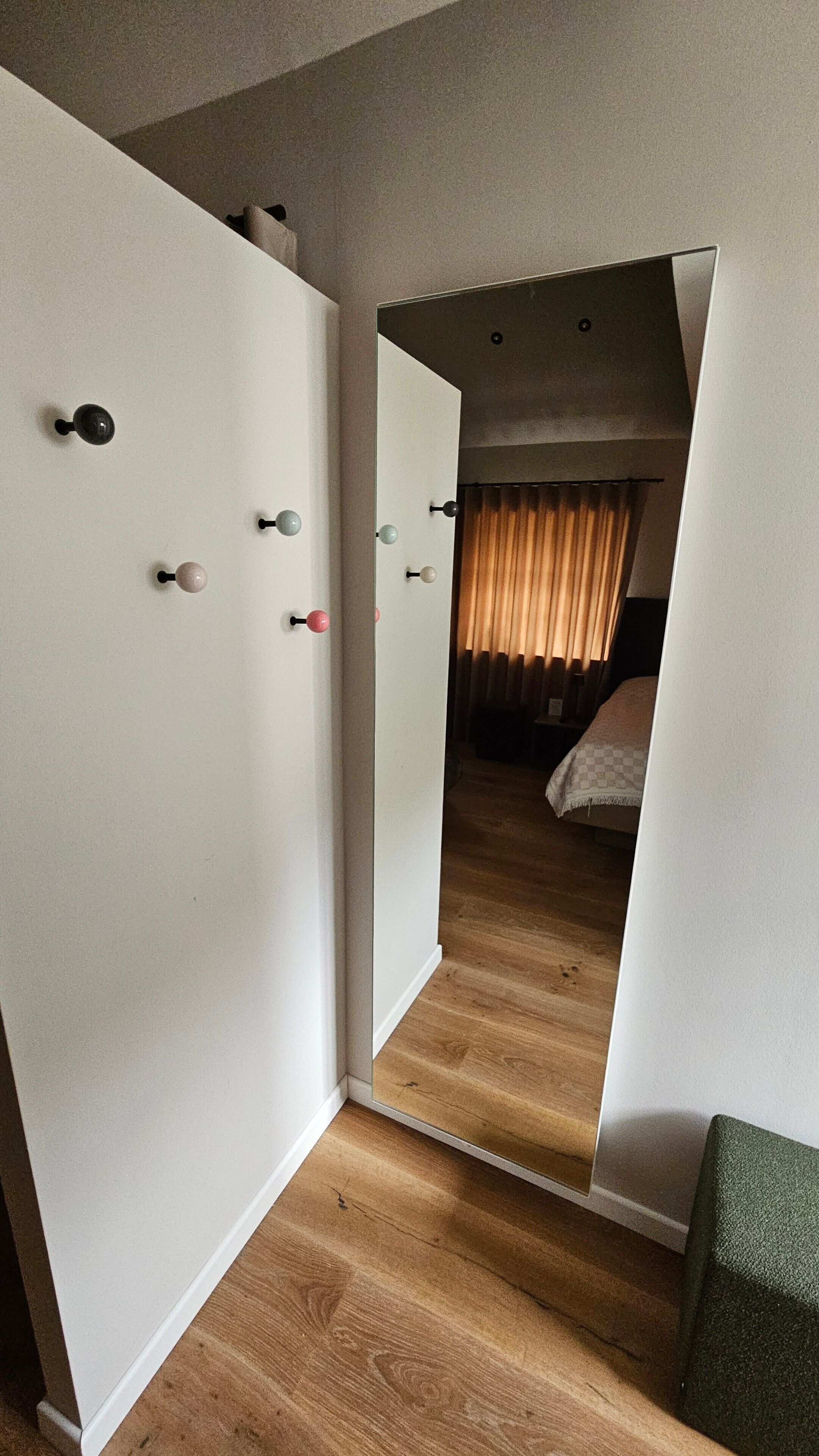 Ein Hotelzimmer mit Holzboden, einem Bett mit kariertem Überwurf und einem Fenster mit Vorhängen.