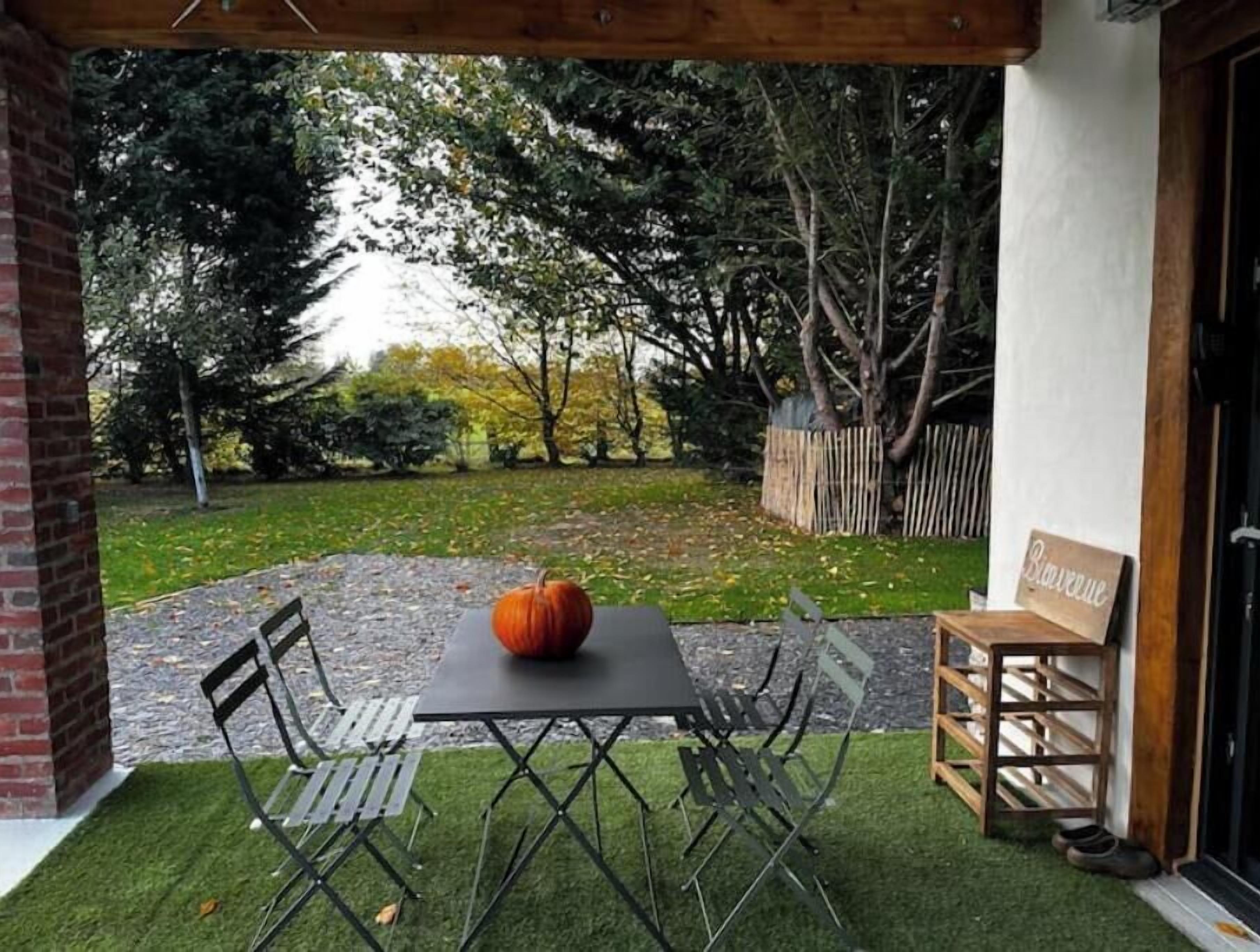 Une terrasse avec une table et des chaises, une citrouille et une pancarte sur laquelle on peut lire « Bienvenue ».