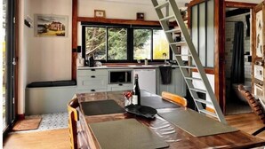 Una cocina moderna con comedor, suelo de madera, estufa empotrada y un amplio ventanal.