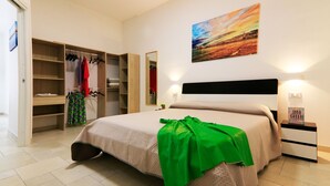 A bedroom with a bed, a wardrobe, a mirror, and a painting on the wall. - Casa Bella (Vieste)
