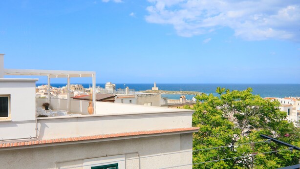 A rooftop terrace with a view of the sea and buildings. - Casa Bella (Vieste)