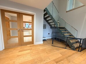 Un intérieur moderne avec un plancher en bois, un escalier en verre et une porte en bois.