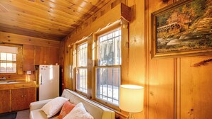 Et kabhytteinteriør med træpaneler, en sofa med puder, et bord med en lampe og et maleri på væggen.