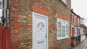 A brick house with a white door labeled "1A" and a window with a white frame. - Headmasters Hollow (Watford)