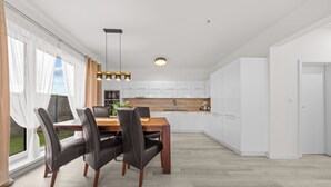 A modern kitchen with white cabinets, a wooden dining table, and black chairs.