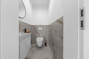 A modern bathroom with a toilet, sink, and mirror. - Air-conditioned Apartment House with Jacuzzi, 9B (Bratislavský kraj)