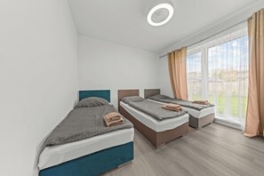 A modern hotel room with two single beds, a large window with curtains, and a ceiling fan. - Air-conditioned Apartment House with Jacuzzi, 9B (Bratislavský kraj)