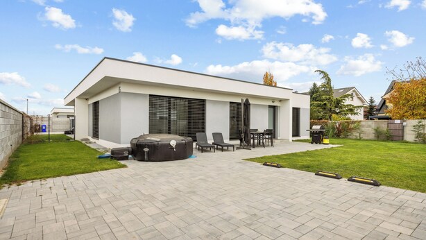 A modern house with a patio area, outdoor seating, and a large water feature.