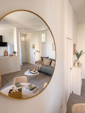 Ein modernes Wohnzimmer mit einem runden Spiegel, einer Couch, einem Couchtisch und einem Essbereich mit Stühlen.