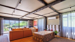 Ein modernes Wohnzimmer mit großem Fenster, einer Couch, einem Holztisch und einer Badewanne.