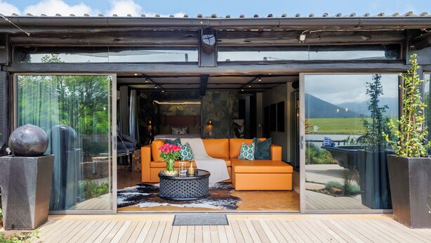 Ein modernes Interieur mit Sofa und Couchtisch, großen Fenstern und einer Holzdiele.