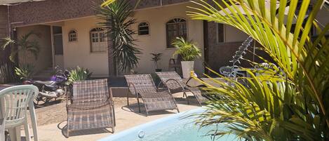 Ein Hotel mit Pool, Liegestühlen und Topfpflanzen.
