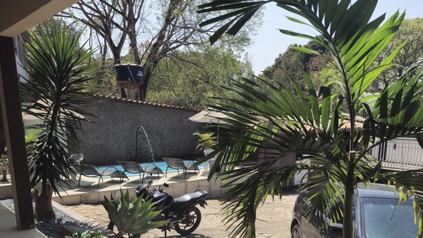 A covered outdoor area with a swimming pool, a motorcycle, and a parked car. - Hotel Vale do Rio (Sao Goncalo do Abaete)