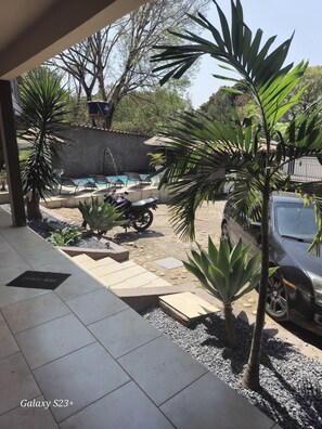 A covered outdoor area with a swimming pool, a motorcycle, and a parked car. - Hotel Vale do Rio (Sao Goncalo do Abaete)