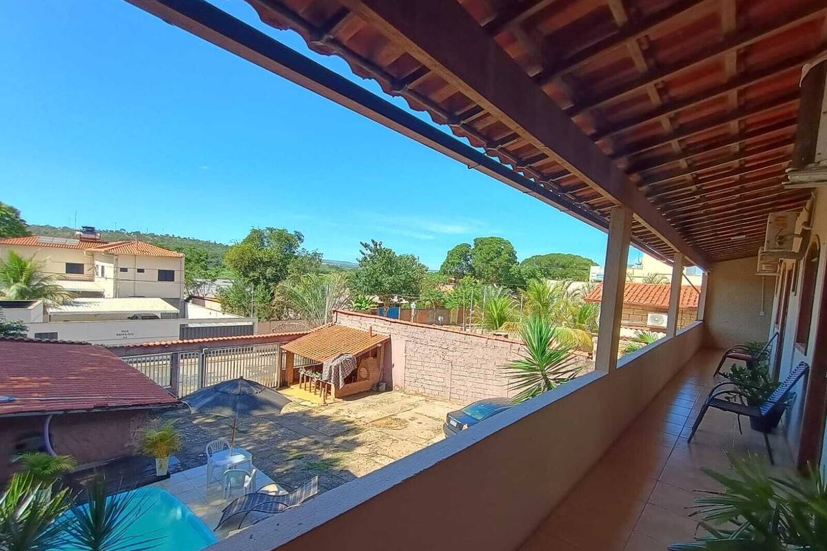 A balcony with a view of a swimming pool, a covered outdoor area, and surrounding buildings.