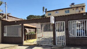A gated entrance to a building with a tiled roof, a signboard, and a parked car inside. - Hotel Vale do Rio (Sao Goncalo do Abaete)