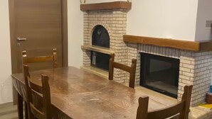 Ein Essbereich mit Holztisch und -stühlen, einem Kamin aus Ziegeln und einer Tür.