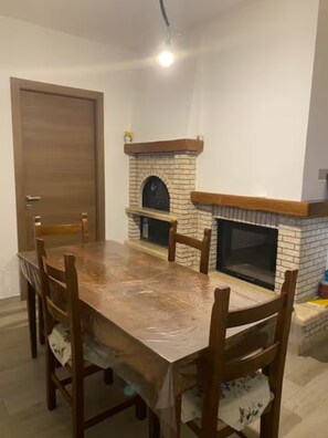 Ein Essbereich mit Holztisch und -stühlen, einem Kamin aus Ziegeln und einer Tür.