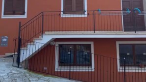 Ein zweistöckiges Gebäude mit Balkon, Satellitenschüssel und geschlossenem Eingangstor.