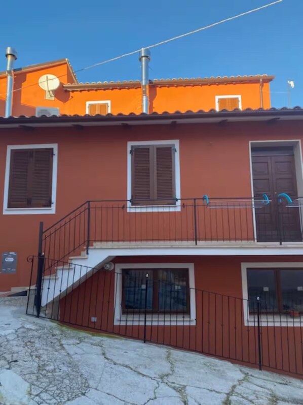 A two-story building with a balcony, a satellite dish, and a gated entrance. - Holiday Home 'Il Focolare dei Sibillini' with Mountain View, Balcony & Wi-Fi (Fematre)