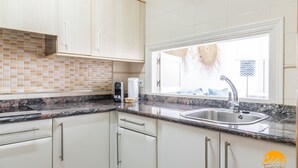 A modern kitchen with white cabinets, granite countertops, a stainless steel sink, and a window with a view. - Loft Victoria Beach Free Parking by C diz Time (Cádiz)
