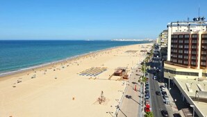 A beachside hotel with a long promenade, beach umbrellas, and a clear view of the ocean. - Loft Victoria Beach Free Parking by C diz Time (Cádiz)