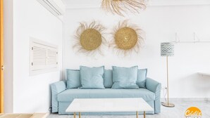 A modern living room with a light blue sofa, a white coffee table, and decorative wall art. - Loft Victoria Beach Free Parking by C diz Time (Cádiz)