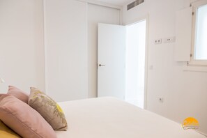 A bedroom with a bed, two pillows, a white door, and a window. - Apartamento Villalobos 8 by C diz Time Apartments (Cádiz)