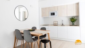 Una cocina moderna con armarios blancos, un microondas y un comedor con mesa y sillas de madera.