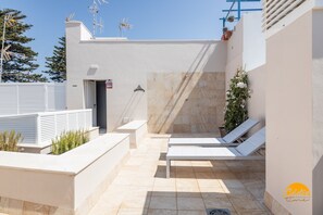 A rooftop terrace with two white lounge chairs, a small door, and a potted plant. - Apartamento Villalobos 6 by C diz Time Apartments (Cádiz)
