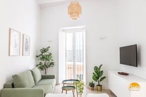 A modern living room with a green sofa, a round table, and a TV mounted on the wall. - Apartamento Villalobos 5 by C diz Time Apartments (Cádiz)